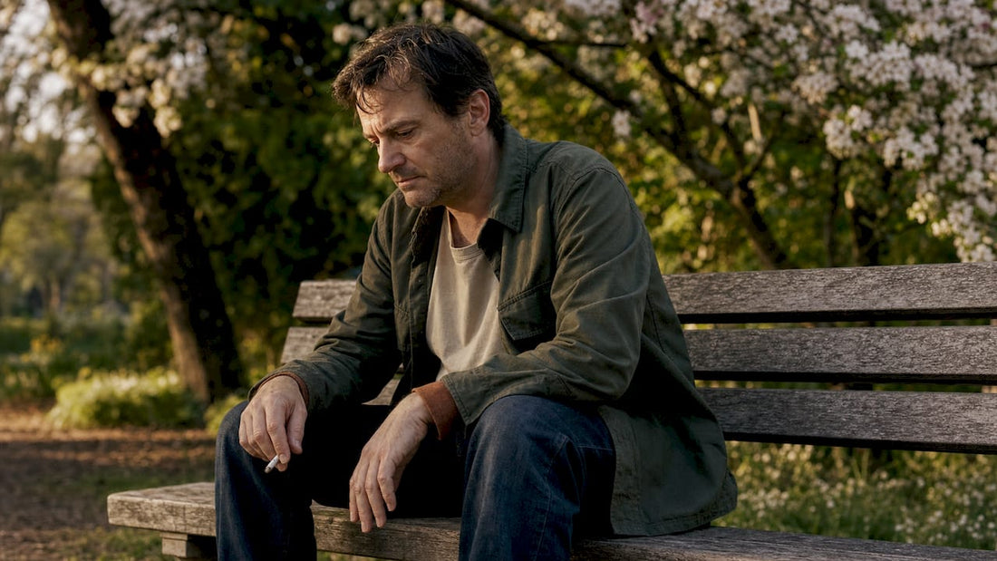 Man sitting on park bench holding cigarette