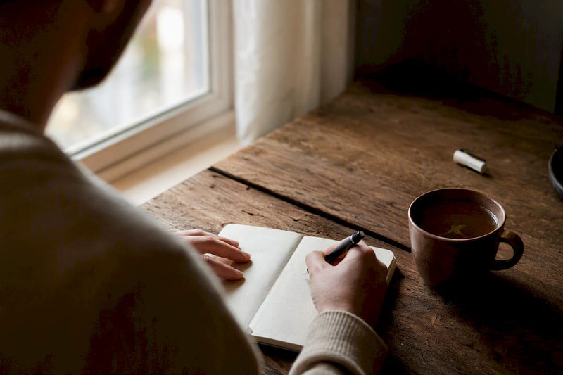 Person writing smoking triggers on notepad