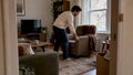 Adult moving an armchair in a living room