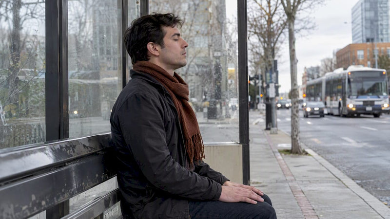 Adult practicing calm nasal breathing at bus shelter