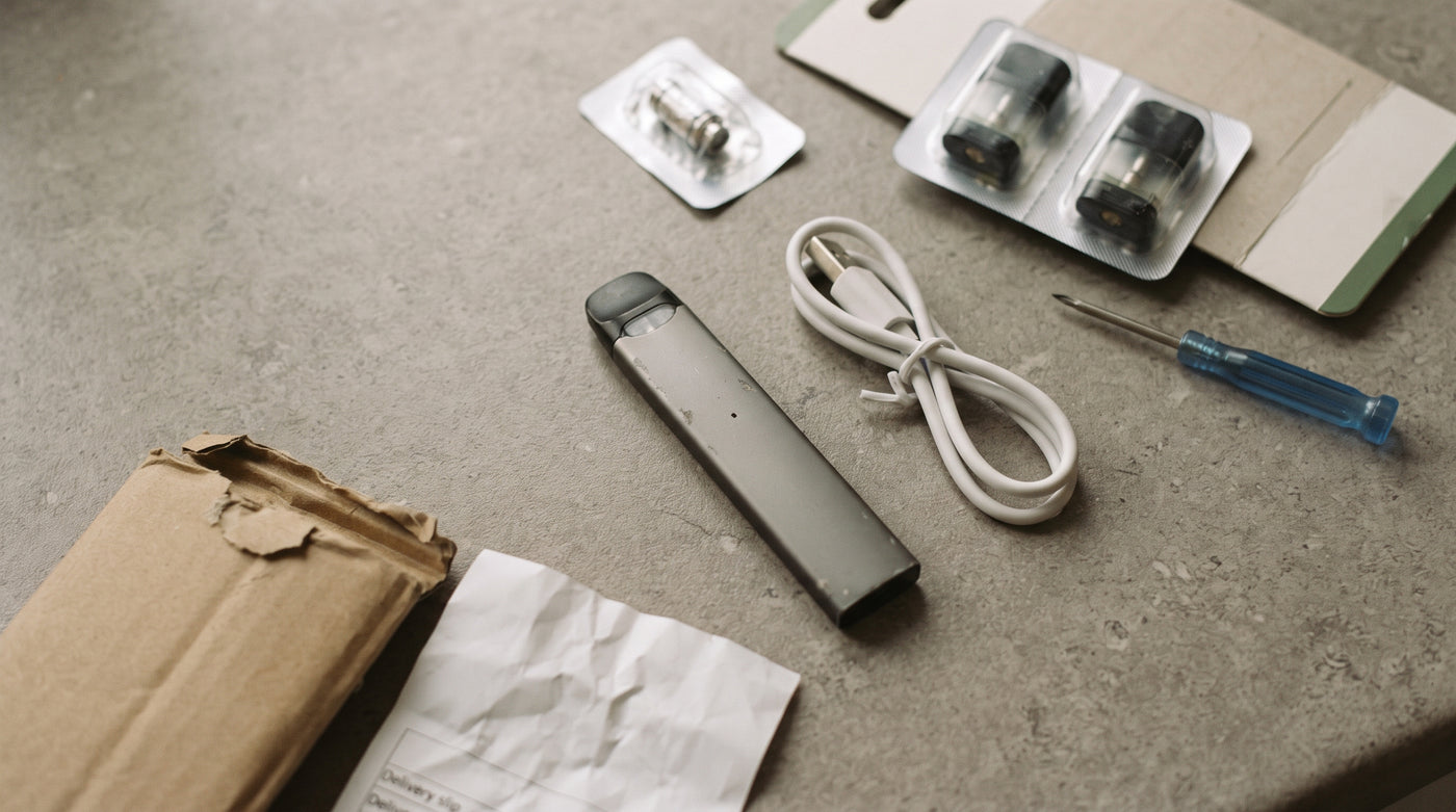 A vape device with its charging cable and spare pods — the whole apparatus a 0mg switch keeps